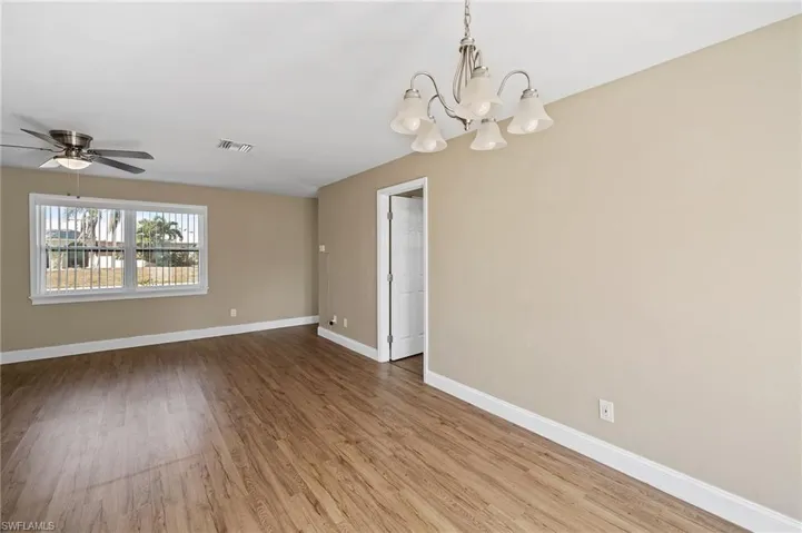 Empty room featuring light wood-style flooring, a chandelier, and ceiling fan