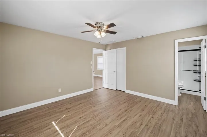 Unfurnished bedroom with wood finished floors, a ceiling fan, and ensuite bathroom