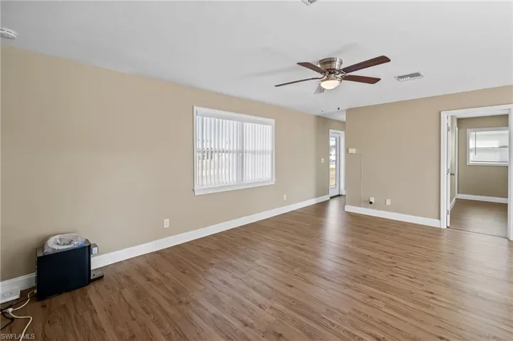 Unfurnished room featuring wood finished floors, a ceiling fan, plenty of natural light, and a smoke detector