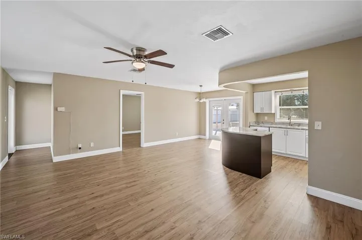 Kitchen with white cabinetry, a chandelier, french doors, decorative light fixtures, and a center island