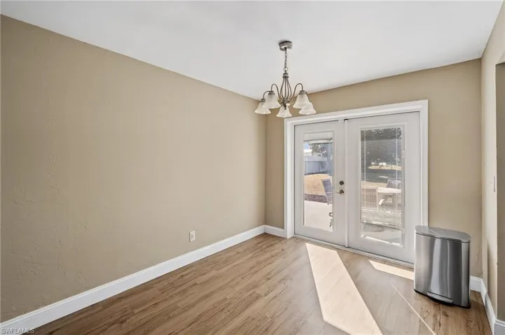 Unfurnished dining area featuring wood finished floors, a chandelier, and french doors