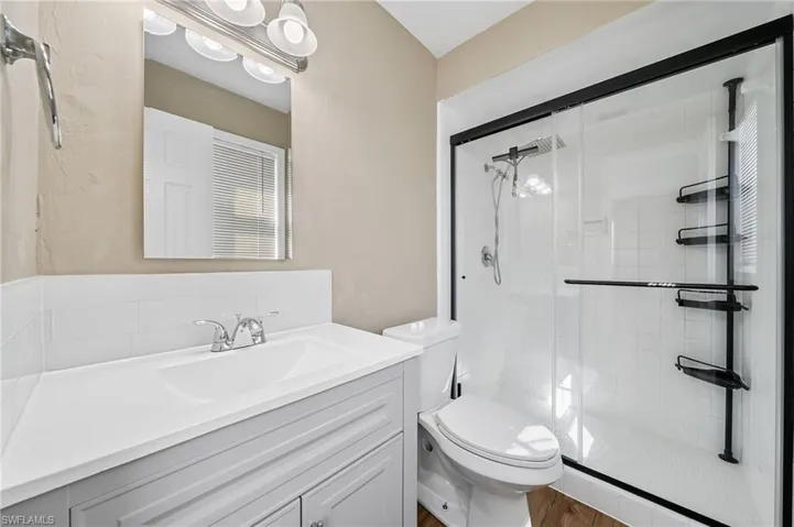 Full bath with a shower stall, vanity, and wood finished floors