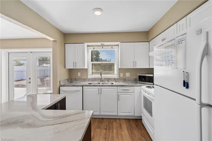 Kitchen with white appliances, white cabinets, french doors, and light wood-type flooring