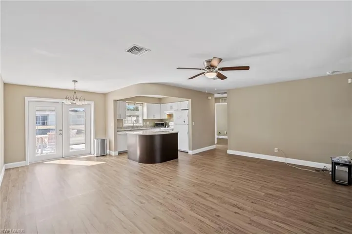 Unfurnished living room with a chandelier, light wood-style floors, and a ceiling fan