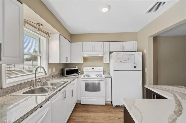 Kitchen featuring white appliances, light wood finished floors, and white cabinets