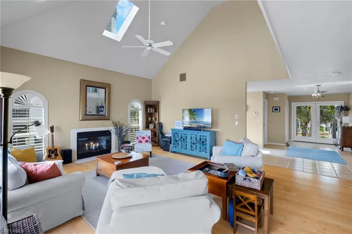 Kitchen with a towering ceiling, appliances with stainless steel finishes, light wood-type flooring, ceiling fan, and decorative light fixtures