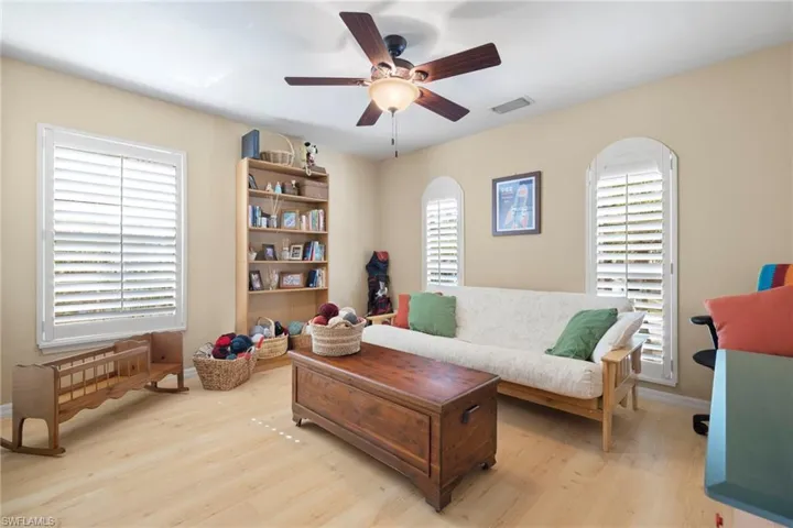 Bedroom featuring ensuite bathroom, light colored carpet, a tray ceiling, and ceiling fan