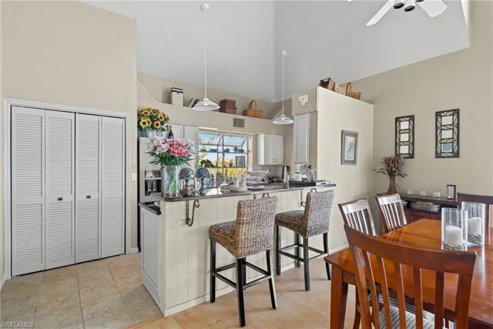 Kitchen with backsplash, dark stone counters, light tile patterned floors, stainless steel dishwasher, and white cabinetry