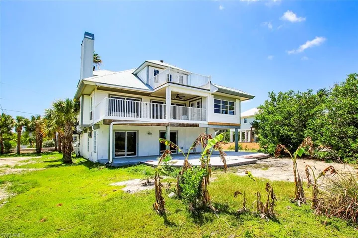 Rear view of property with a yard, a patio area, and a balcony
