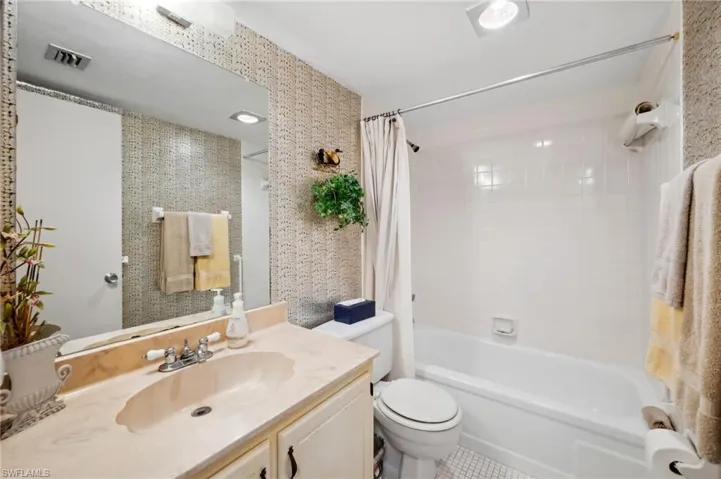 Full bath with visible vents, shower / bathtub combination with curtain, toilet, and vanity