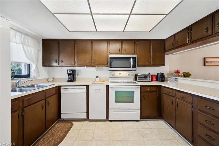 Kitchen featuring white appliances, light countertops, and a sink