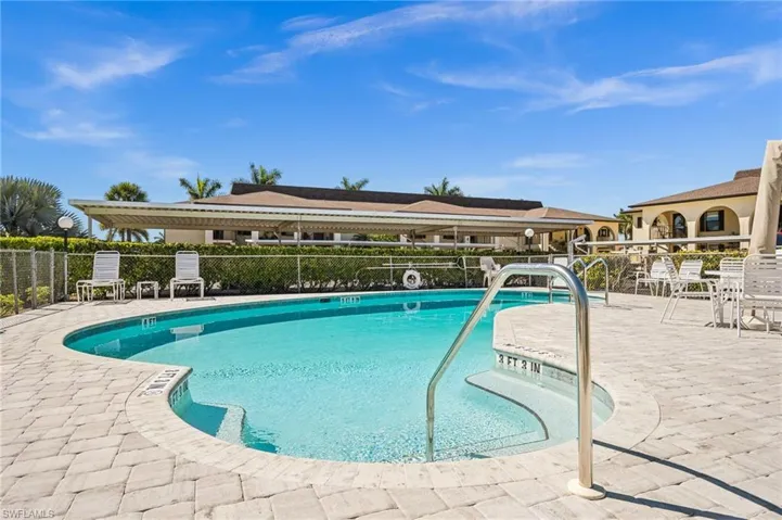 Community pool with a patio area and fence