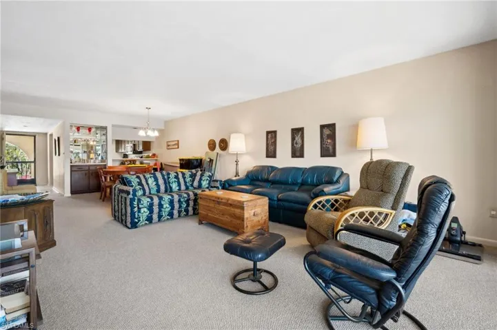 Living area featuring baseboards, carpet, and an inviting chandelier
