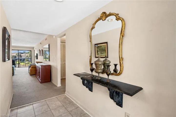 Hallway with baseboards, light carpet, and light tile patterned flooring