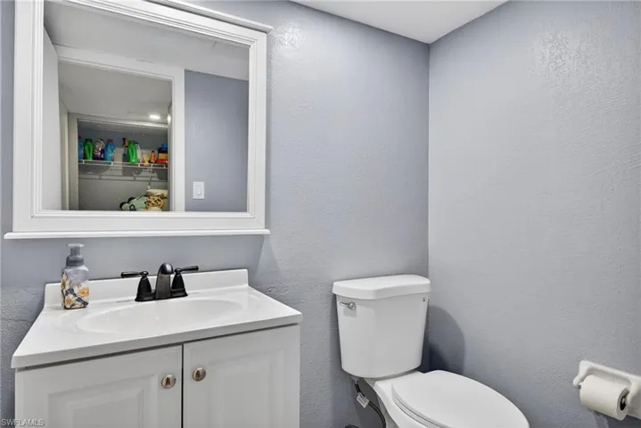 Half Bathroom with vanity and a textured wall