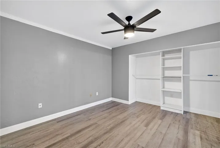 Unfurnished bedroom featuring light wood finished floors, ceiling fan, ornamental molding, and a closet