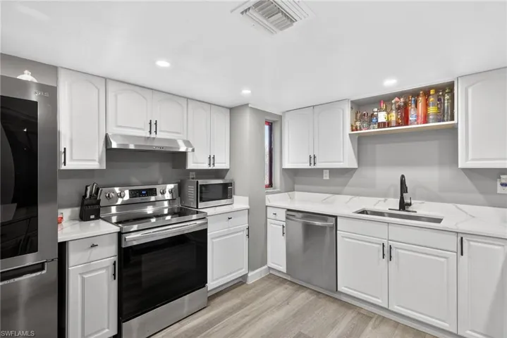 Kitchen featuring stainless steel appliances, white cabinets, light wood-style floors, and recessed lighting