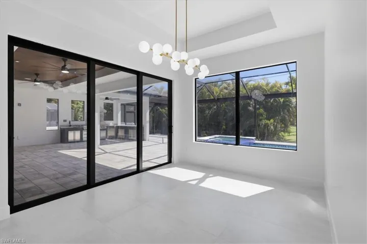 Spare room featuring a tray ceiling, ceiling fan, hanging lights, and tile patterned floors