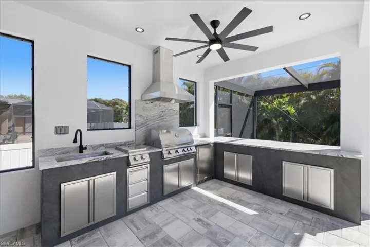 View of patio / terrace featuring an outdoor kitchen, a sunroom, glass enclosure, and ceiling fan