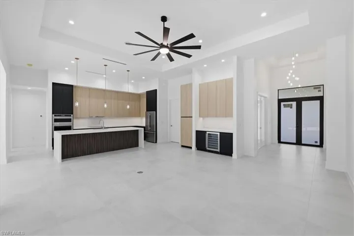 Unfurnished living room featuring a tray ceiling, beverage cooler, ceiling fan, recessed lighting, and french doors