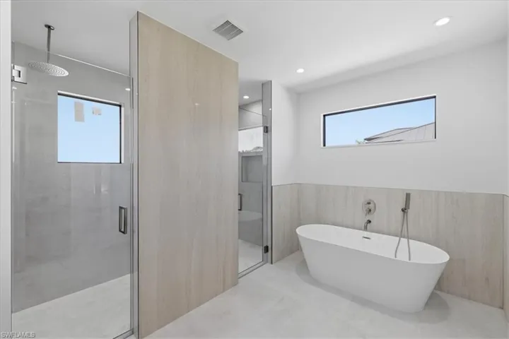 Full bathroom with wainscoting, a stall shower, a freestanding bath, and recessed lighting