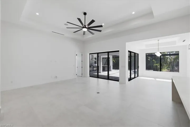 Empty room with a tray ceiling, ceiling fan, and recessed lighting