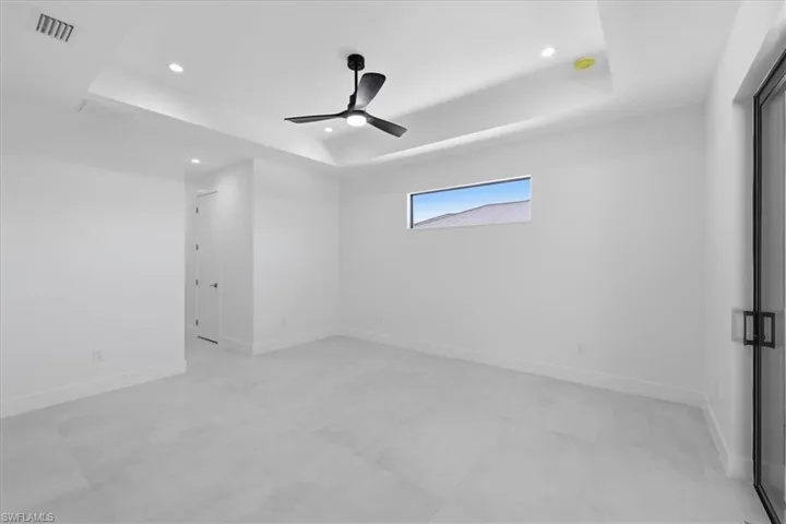 Empty room featuring recessed lighting, a ceiling fan, and a tray ceiling
