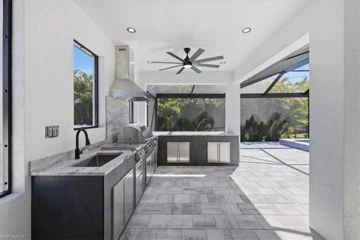 View of patio with an outdoor kitchen, a sunroom, ceiling fan, and glass enclosure