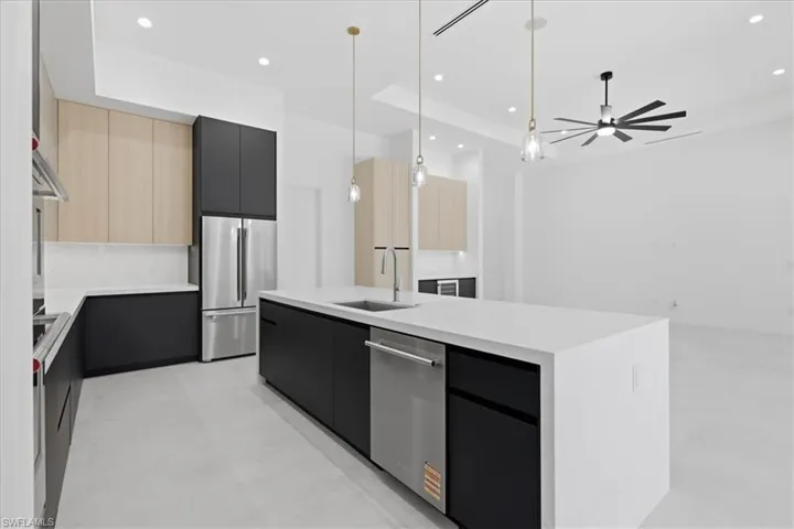 Kitchen with dual tone cabinets, modern cabinets, a kitchen island with sink, decorative light fixtures, and stainless steel appliances