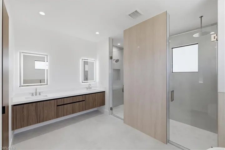 Bathroom featuring a stall shower, double vanity, and recessed lighting