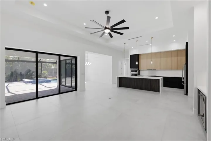 Two tone kitchen with a center island, modern cabinets, open floor plan, ceiling fan, and stainless steel appliances