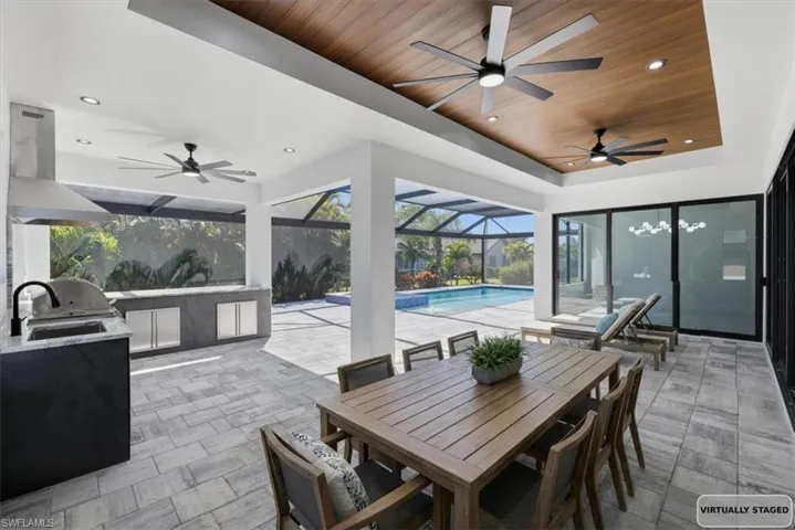 View of patio / terrace featuring an outdoor kitchen / dining area, an outdoor pool, ceiling fan, a sunroom, and glass enclosure