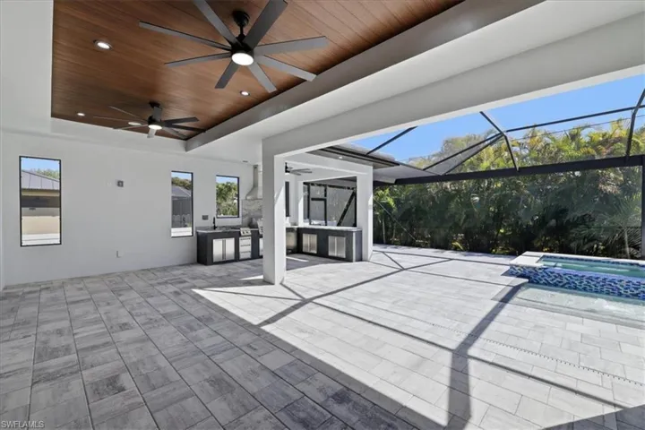 View of patio featuring a sunroom, a lanai, a ceiling fan, a pool with connected hot tub, and area for grilling