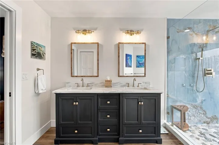 The primary bath feels like a private spa with dual vanities featuring quartz countertops, custom cabinetry, and designer lighting that adds a polished, luxurious glow.