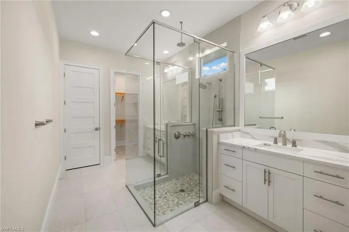 Primary bathroom features dual vanities & frameless shower