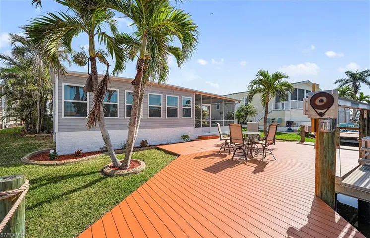 Deck featuring a boat dock, a sunroom, and a lawn