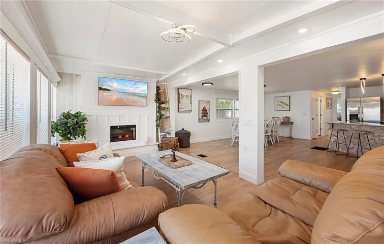 Living room with lofted ceiling with beams and light hardwood / wood-style floors
