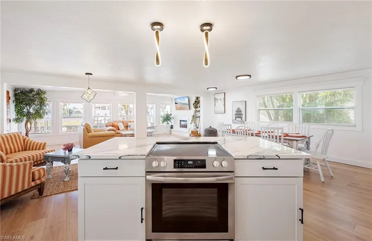 Kitchen with white cabinetry, light hardwood / wood-style floors, light stone counters, and stainless steel electric range