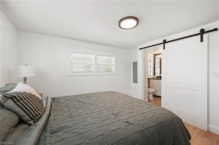 Bedroom featuring light hardwood / wood-style floors, a barn door, and ensuite bathroom