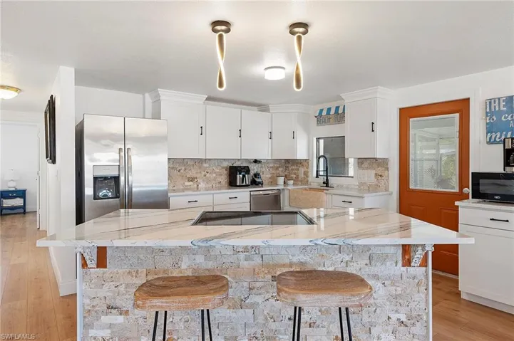 Kitchen with light stone countertops, a kitchen island, a breakfast bar, and black appliances
