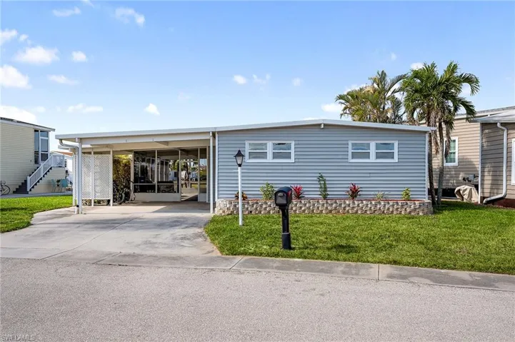 Manufactured / mobile home with a front lawn and a carport