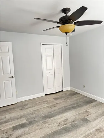 Unfurnished bedroom with light wood-style flooring, ceiling fan, and a closet
