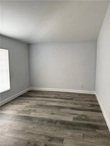 Unfurnished room with dark wood finished floors and baseboards
