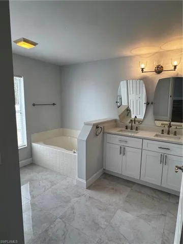Full bathroom featuring a bath and double vanity