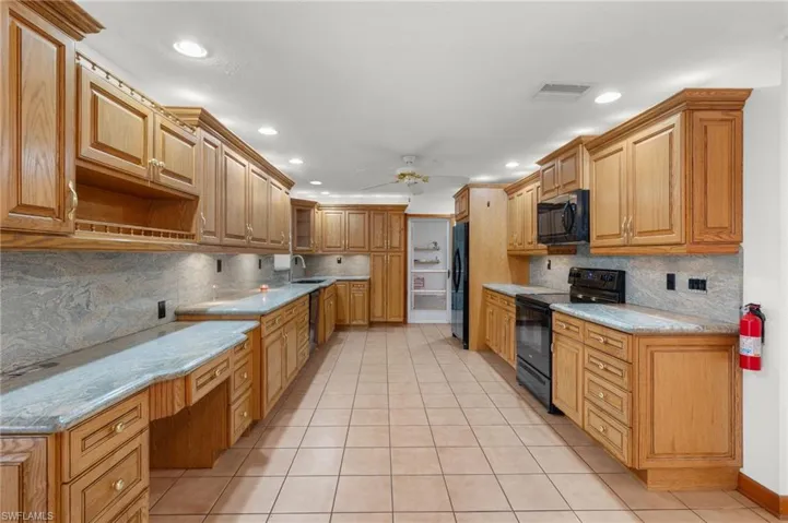 Kitchen with black appliances, ceiling fan, light tile floors, and tasteful backsplash