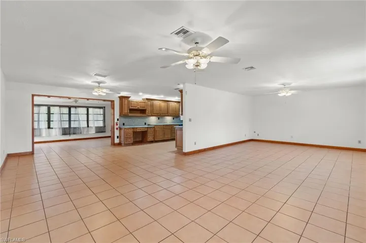 Unfurnished living room with ceiling fan and light tile flooring