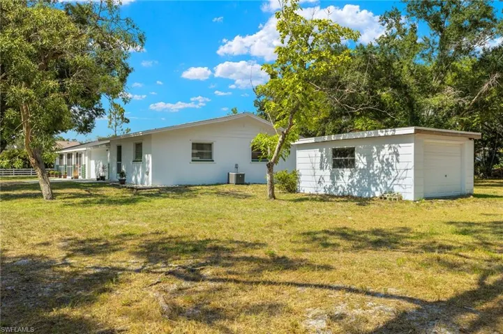 Back of property featuring a garage and a lawn