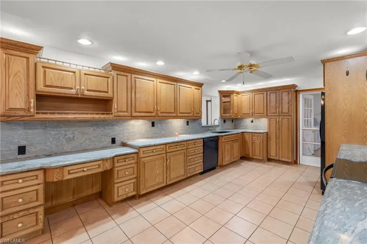 Kitchen with ceiling fan, dishwasher, backsplash, light tile floors, and sink