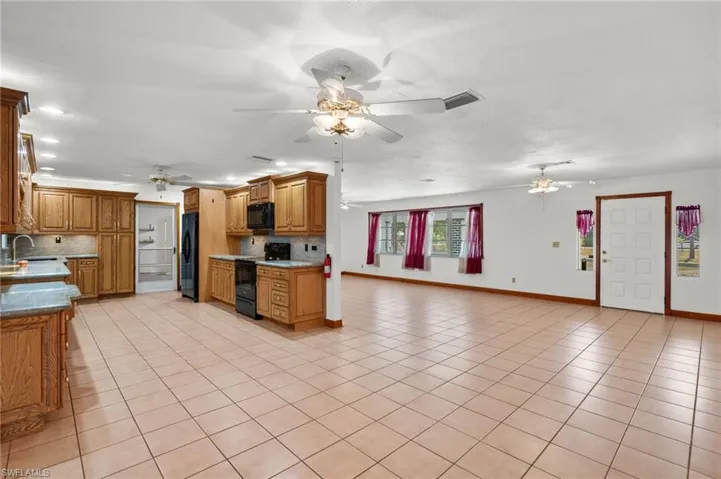 Kitchen featuring backsplash, black appliances, ceiling fan, and light tile floors