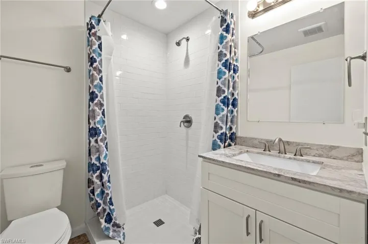 Bathroom with a shower with shower curtain, toilet, and vanity